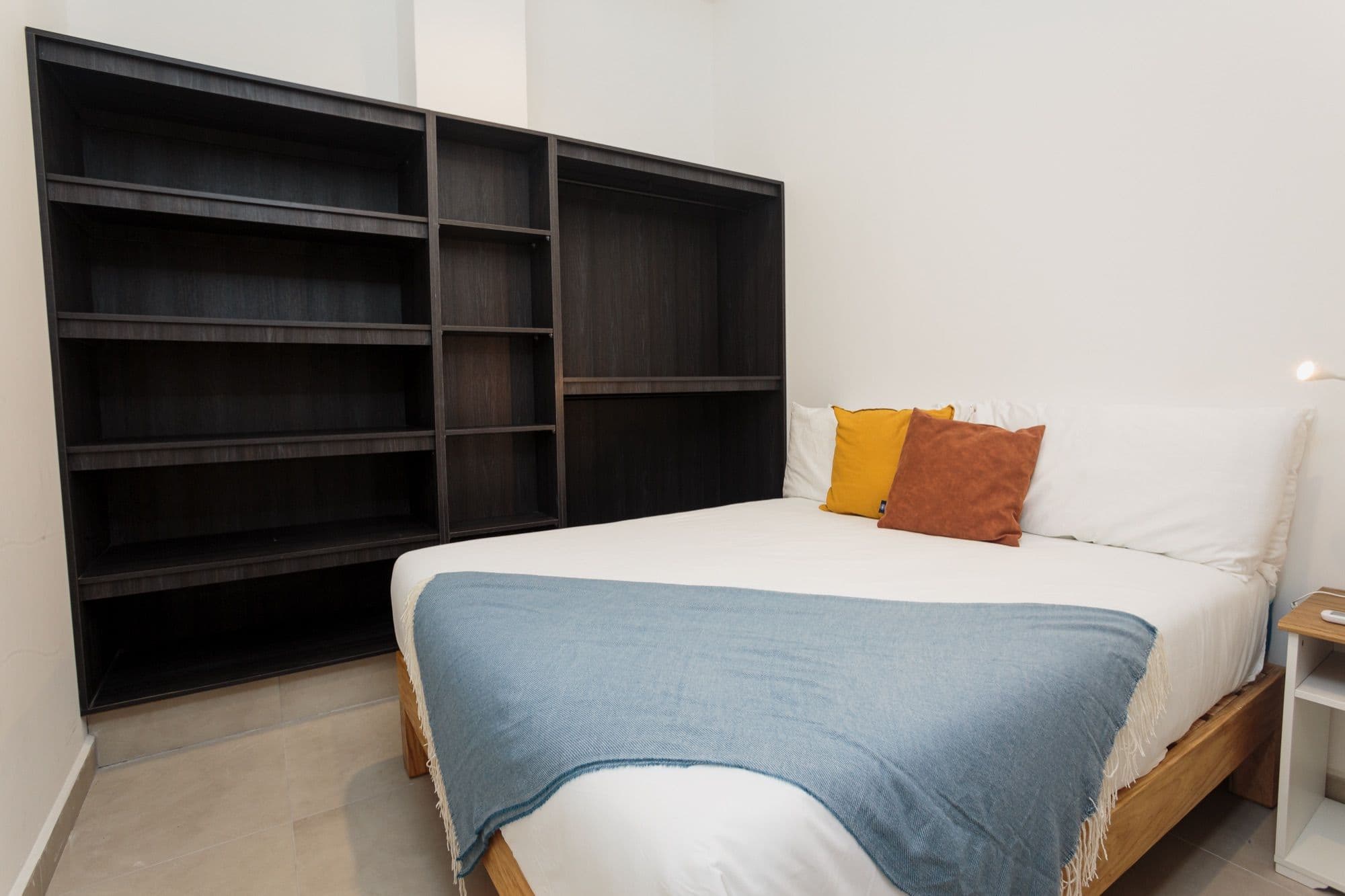Sol bedroom with open shelving and a woven throw.